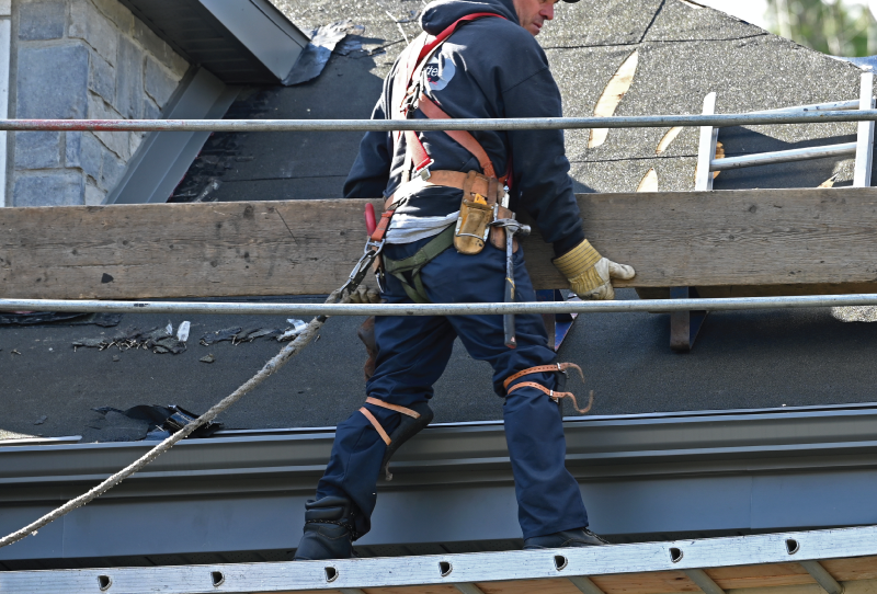 Un ouvrier tenant un madrier lors du montage d'un échafaud avant la réparation d'un toit en pente